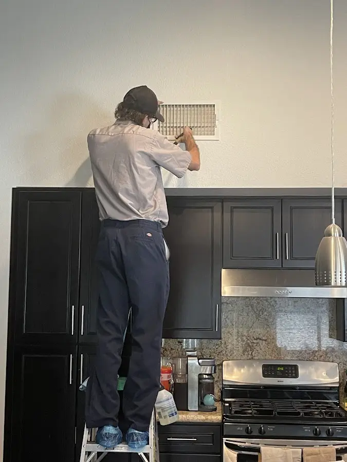 Technician inspecting an air vent during HVAC service in Ohio